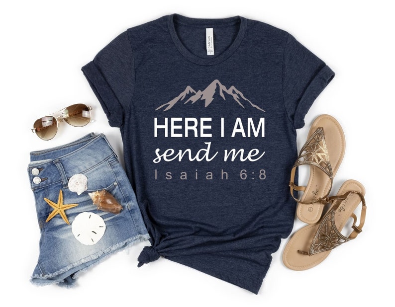 May include: A navy blue t-shirt with a white graphic of mountains and the text "HERE I AM send me Isaiah 6:8".