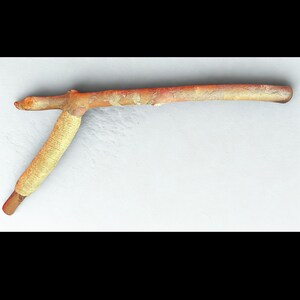 May include: A handcrafted wooden tool with a T-shaped design. The handle is wrapped with tan-coloured twine, and the wood has a natural, light brown colour with some reddish hues. The tool appears to be made from a branch.