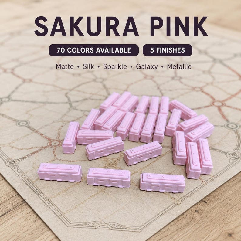 May include: A collection of small, rectangular, light pink game pieces with molded details. The text SAKURA PINK, 70 COLORS AVAILABLE, 5 FINISHES, and the list Matte, Silk, Sparkle, Galaxy, Metallic are displayed above the game pieces.