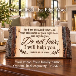 May include: A rectangular live edge wood plaque featuring a natural bark border on the left and right sides. The centre is light-coloured wood engraved with the text: For I am the Lord your God who takes hold of your right hand and says to you, Do not fear; I will help you. ISAIAH 41:13 • NIV, with small leaf accents.