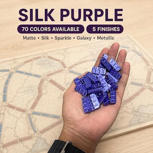 May include: A collection of small, purple, rectangular train-shaped game pieces with a silk finish. Text on the image reads: SILK PURPLE, 70 COLORS AVAILABLE, 5 FINISHES, Matte, Silk, Sparkle, Galaxy, Metallic, over a board game map.