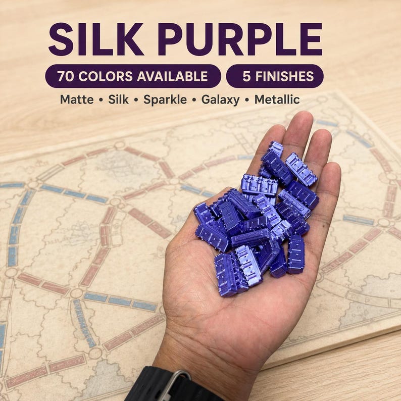 May include: A collection of small, purple, rectangular train-shaped game pieces with a silk finish. Text on the image reads: SILK PURPLE, 70 COLORS AVAILABLE, 5 FINISHES, Matte, Silk, Sparkle, Galaxy, Metallic, over a board game map.