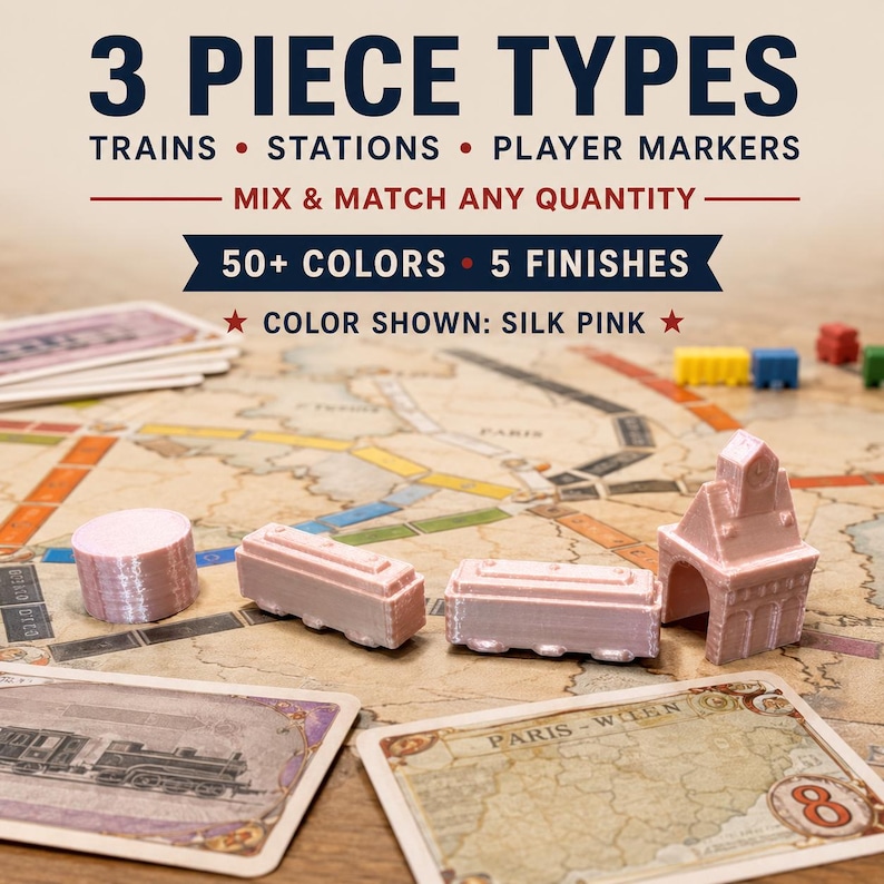 May include: A set of silk pink board game pieces including a cylindrical marker, two rectangular train cars, and a station building. Text reads: 3 PIECE TYPES, TRAINS, STATIONS, PLAYER MARKERS, MIX & MATCH ANY QUANTITY, 50+ COLORS, 5 FINISHES, COLOR SHOWN: SILK PINK.
