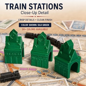 May include: Three silk green 3D-printed train station game pieces with arched doorways and clock tower details. Text on the image reads: TRAIN STATIONS, Close-Up Detail, CRISP DETAILS &bull; CLEAN FINISH, COLOR SHOWN: SILK GREEN, 50+ COLORS AVAILABLE.