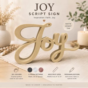 May include: A matte desert tan script sign featuring the word Joy in a cursive font. The sign is freestanding with a thick profile. Text on the image includes JOY SCRIPT SIGN, Inspiration. Faith. Joy., 30+ COLORS, 3 FINISH OPTIONS, MULTIPLE SIZES Widths from 10 cm to 36 cm, and PERSONALISATION.