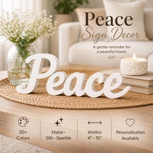 May include: A white wooden sign featuring the word Peace in a cursive script font. The sign is displayed on a round woven mat alongside a glass vase with white flowers and a white candle. Text on the image includes Peace Sign Decor, 30+ Colors, Matte, Silk, Sparkle, Widths 4-15 inches, and Personalization Available.
