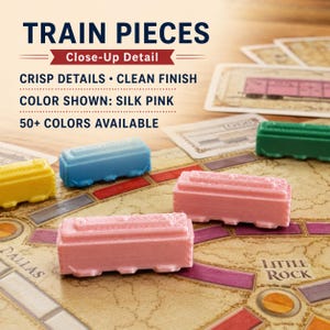 May include: Small plastic train pieces in yellow, blue, pink, and green colors resting on a board game map. Text on the image reads: TRAIN PIECES, Close-Up Detail, CRISP DETAILS &bull; CLEAN FINISH, COLOR SHOWN: SILK PINK, 50+ COLORS AVAILABLE.