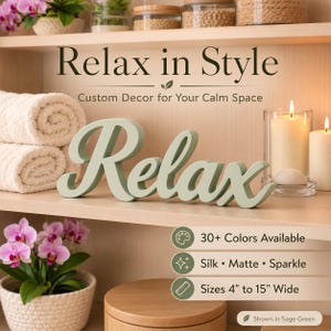May include: A sage green wooden sign with the word Relax in a cursive font. The sign is displayed on a shelf with white towels, candles, and a potted orchid. Text on the image includes Relax in Style, Custom Decor for Your Calm Space, 30+ Colors Available, Silk, Matte, Sparkle, and Sizes 10 cm to 38 cm Wide.
