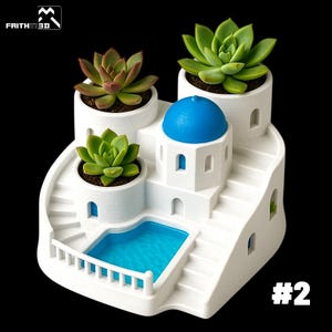 Peut inclure: Un pot de fleurs blanc à plusieurs niveaux avec une mini-piscine et des escaliers, ressemblant à une île grecque. Il présente trois plantes succulentes dans des pots blancs, un dôme bleu et le texte "#2".