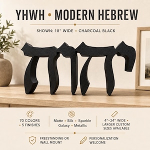 May include: A charcoal black freestanding sign featuring the Hebrew word Chai in a modern script. The text YHWH MODERN HEBREW is displayed above, with SHOWN: 18" WIDE • CHARCOAL BLACK. Below, icons indicate 70 colors, 5 finishes, and 4"–24" wide sizing.