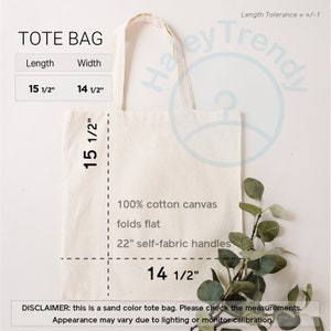 Op de afbeelding: Een zandkleurige tote bag gemaakt van 100% katoenen canvas met 22 inch zelfgemaakte handvatten. De tas is 15 1/2 inch lang en 14 1/2 inch breed. De tekst "TOTE BAG" is bovenaan de tas gedrukt.