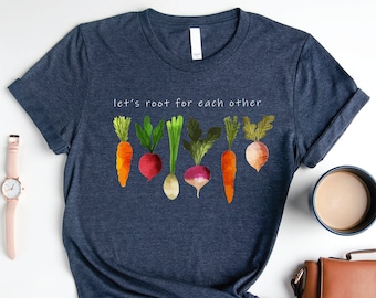 May include: A navy blue t-shirt with the text "let's root for each other" and a graphic of colorful vegetables, including carrots, radishes, and turnips.