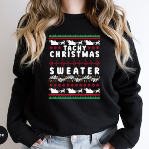 May include: Black Christmas sweater with a green, red, and white design. The sweater features a heart rate monitor graphic and the text "Tachy Christmas Sweater".