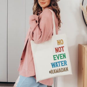 Op de afbeelding: Een witte tote bag met de tekst "NO NOT EVEN WATER #RAMADAN" in kleurrijke letters. De tekst is verticaal gestapeld, waarbij elk woord een andere kleur heeft.