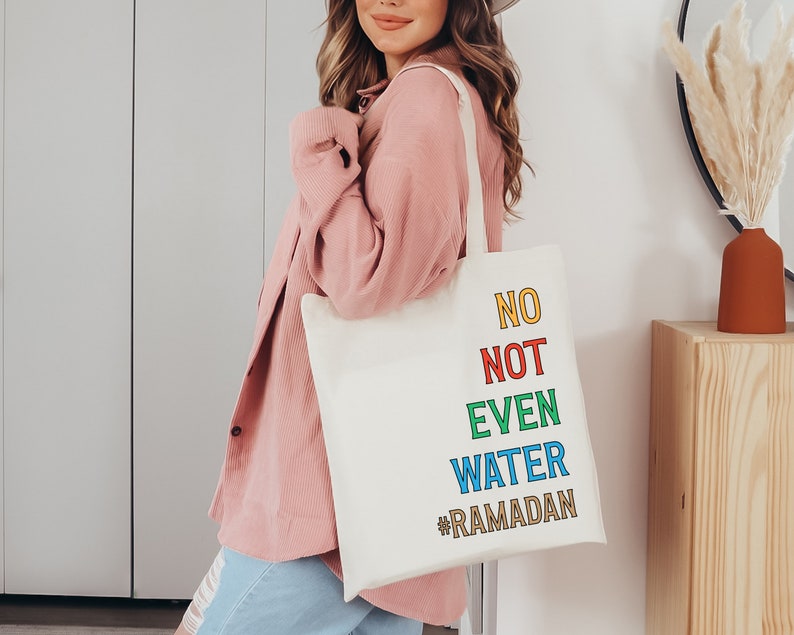 Op de afbeelding: Een witte tote bag met de tekst "NO NOT EVEN WATER #RAMADAN" in kleurrijke letters. De tekst is verticaal gestapeld, waarbij elk woord een andere kleur heeft.