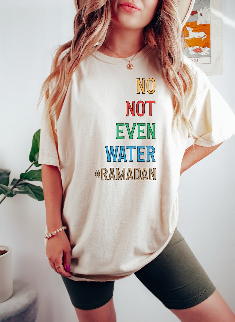 Op de afbeelding: Een wit T-shirt met de tekst "NO NOT EVEN WATER #RAMADAN" in kleurrijke letters.