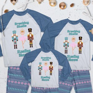 May include: Three long-sleeve raglan shirts with white bodies and blue sleeves, paired with blue patterned pajama pants. The shirts feature two nutcracker figures and a ballerina with the text Breaking Shells and Stealing Shows printed in blue.