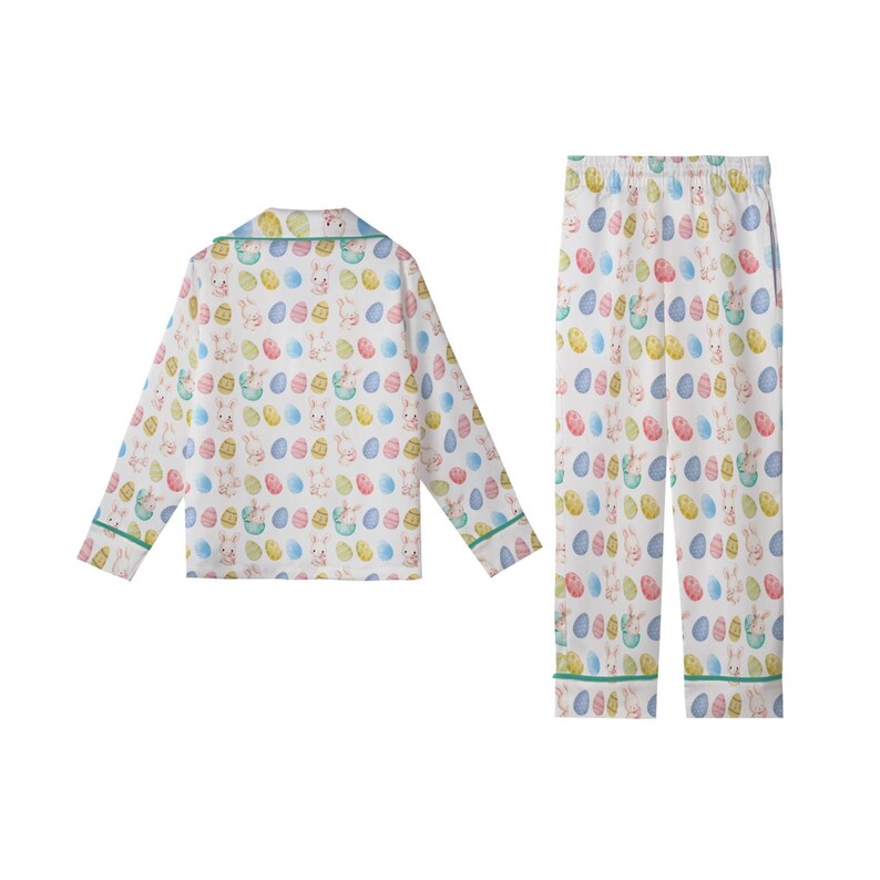 May include: White pyjama set with a colourful Easter-themed print. The long-sleeved top and trousers feature a pattern of pastel-coloured Easter eggs and bunnies. The set has green trim on the collar, cuffs, and trouser hems.