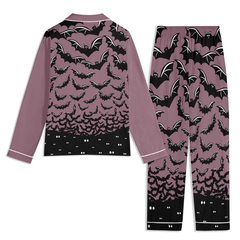 May include: A long-sleeve button-down pajama top and matching pajama pants in a dusty mauve color. The set features an all-over print of black bats, transitioning into a solid black hemline at the bottom with small white glowing eyes.