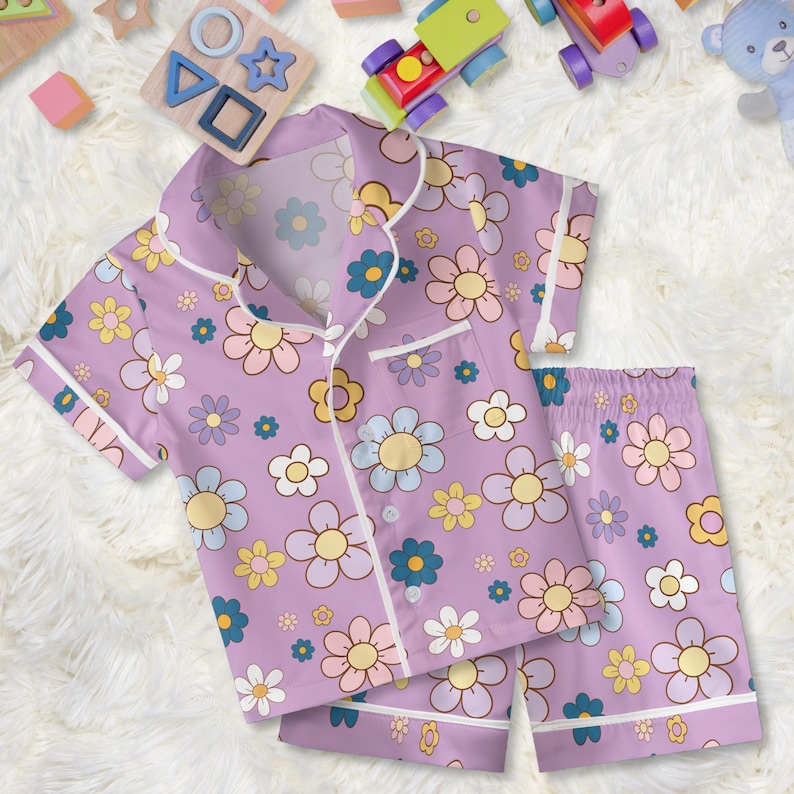 Puede incluir: Conjunto de pijama lila para ni&ntilde;os con estampado floral en tonos amarillo, azul, rosa y blanco. La parte superior de manga corta y los pantalones cortos tienen ribetes blancos. El conjunto est&aacute; hecho de una tela suave y ligera, ideal para dormir.