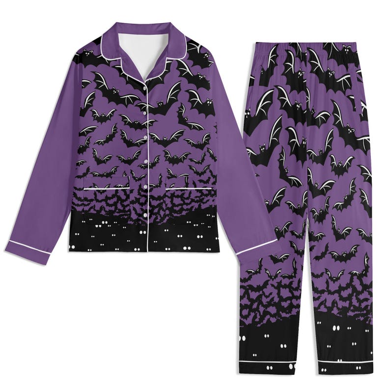 May include: A long-sleeve button-down pajama shirt and matching pants set in purple. The fabric features a repeating pattern of black bats flying against a purple background, transitioning to a solid black hem with white glowing eyes at the bottom.