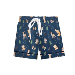Puede incluir: Pantalones cortos azul marino con cord&oacute;n blanco. Los pantalones cortos presentan un estampado repetido de animales del bosque, incluyendo ciervos, ardillas, osos y b&uacute;hos, junto con &aacute;rboles y setas. Los pantalones cortos tienen un ribete azul marino.