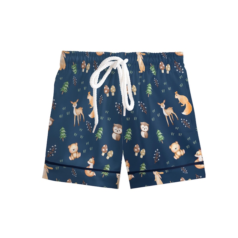 Puede incluir: Pantalones cortos azul marino con cord&oacute;n blanco. Los pantalones cortos presentan un estampado repetido de animales del bosque, incluyendo ciervos, ardillas, osos y b&uacute;hos, junto con &aacute;rboles y setas. Los pantalones cortos tienen un ribete azul marino.