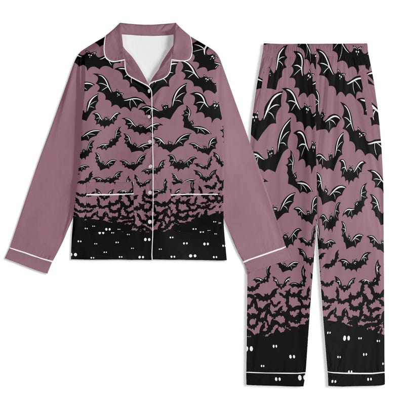 May include: A two-piece pajama set featuring a long-sleeved button-down shirt and matching pants. The fabric is a dusty mauve color with a repeating pattern of black bats. The bottom hem of the shirt and pants features a solid black border with white eyes.