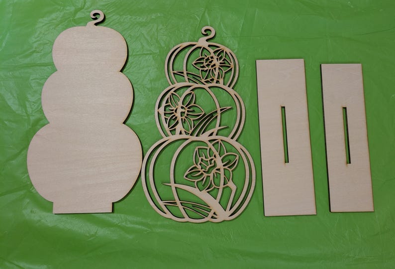 Op de afbeelding: Ongefinished houten pompoenvormige uitsparingen en steunstukken. Een effen pompoenvorm, een decoratieve pompoen met bloemuitsparingen en twee rechthoekige steunen met sleuven. Perfect voor herfst DIY decoratie.