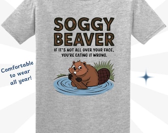 May include: A gray t-shirt with a cartoon beaver in a pond and the text "Soggy Beaver" and "If it's not all over your face, you're eating it wrong."
