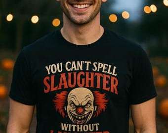 May include: Black t-shirt with the text "YOU CAN'T SPELL SLAUGHTER WITHOUT LAUGHTER" and a scary clown graphic. The clown has red hair, a red nose, and a sinister grin. The shirt is worn by a person smiling at the camera.