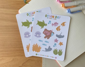 May include: Two sticker sheets with an ocean theme. The sticker sheets feature a variety of sea creatures, including a turtle, a bear with a snorkel, a stingray, a starfish, and seaweed. The sticker sheets are labeled "Ocean Day Sticker Sheet" and "On My Days Off Studio".