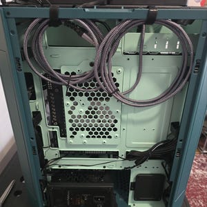 K&ouml;nnte beinhalten: Ein offenes Computergeh&auml;use mit tealfarbenem &Auml;u&szlig;eren und hellgr&uuml;nem Inneren. Geflochtene graue Kabel sind ordentlich im Inneren angeordnet. Ein Netzteil und andere Komponenten sind sichtbar.