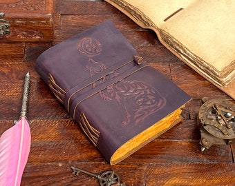 May include: A purple leather journal with a wolf design embossed on the cover. The journal has a decorative closure and is closed.