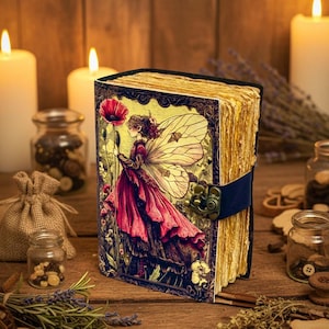 Peut inclure: Un journal décoratif avec une illustration de fée sur la couverture. La fée porte une robe rouge et tient un coquelicot. Le journal est fermé par une sangle bleue et un fermoir en métal. Les pages sont jaunies.