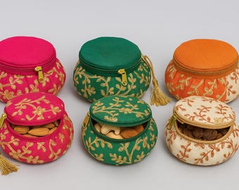 May include: Six small, round, zippered pouches in various colors: fuchsia, green, and orange. Each pouch is embroidered with gold floral patterns and contains nuts. Tassels hang from the zippers.