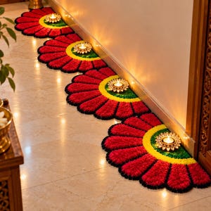 Può includere: Una serie di quattro tappetini semicircolari disposti in fila, ognuno caratterizzato da un motivo a petali rosso vivace con un centro giallo brillante e un anello interno verde. Ogni tappetino ospita una piccola lampada diya dorata accesa.