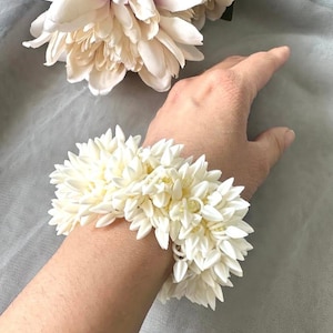 Op de afbeelding: Een witte keramische mok met een zwarte handgreep en de tekst "But First, Coffee" in een vetgedrukte, zwarte letter. De mok staat tegen een vage achtergrond, wat een gezellige setting suggereert.