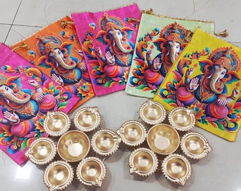 May include: An assortment of colorful drawstring bags featuring a vibrant illustration of the Hindu deity Ganesha, alongside several gold-colored oil lamps. The bags are in shades of pink, orange, green, and yellow.