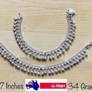 May include: Two silver anklets with dangling beads. The anklets are 7 inches long and weigh 34 grams.