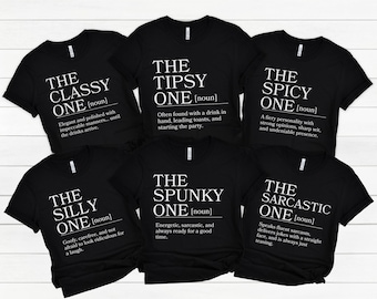 May include: Six black short-sleeved t-shirts featuring white text definitions. The shirts are labeled as The Classy One, The Tipsy One, The Spicy One, The Silly One, The Spunky One, and The Sarcastic One, each with a unique descriptive definition.
