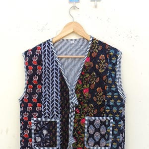 Puede incluir: Un chaleco acolchado negro con estampado floral y dos bolsillos. El chaleco tiene cuello en V y cierre de corbata.