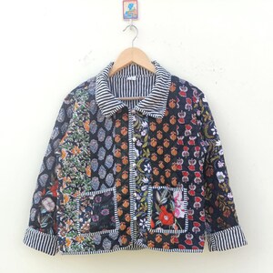 May include: A black quilted jacket with a floral print and a striped collar. The jacket has two patch pockets on the front.
