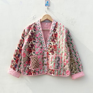 May include: A quilted jacket with a floral print in shades of pink, red, and green. The jacket has a button closure and two patch pockets.