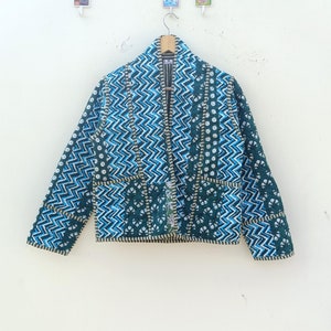 Puede incluir: Una chaqueta con estampado azul y verde con un diseño en zigzag. La chaqueta tiene cuello y cierre frontal.