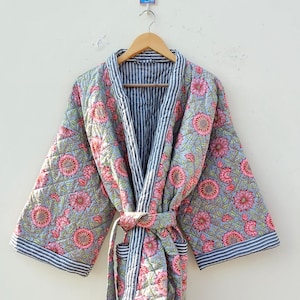 Könnte beinhalten: Eine graue und weiße gestreifte Baumwollrobe mit Blumendruck. Die Robe hat einen Bindegürtel und zwei Taschen.