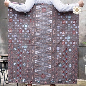 May include: A brown and gray patterned sarong with a geometric design. The sarong has a white border and is made of a soft, lightweight fabric.