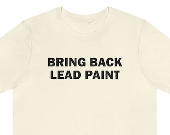 May include: A cream-colored t-shirt with black text that reads "BRING BACK LEAD PAINT".