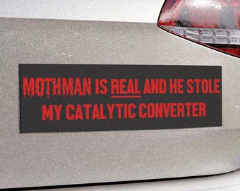 May include: A black and red bumper sticker on a silver car that reads "Mothman is real and he stole my catalytic converter."