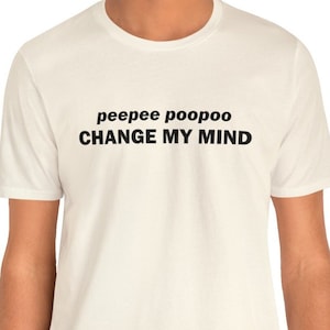 Puede incluir: Camiseta color crema con el texto "peepee poopoo CHANGE MY MIND" impreso en negro. La camiseta tiene mangas cortas y cuello redondo.